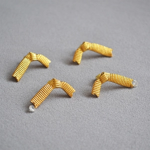 Detailed view of gold V-shaped stud earrings with textured finish and crystal accents