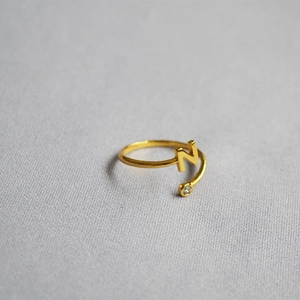 Detail of adjustable gold ring featuring an initial N letter and a sparkling zircon stone