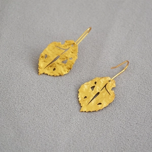Detailed macro view of vintage gold leaf earrings with a hammered matte texture finish