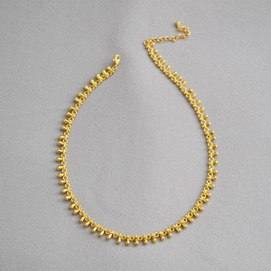 Detailed view of gold plated brass necklace with small teardrop charms and lobster clasp