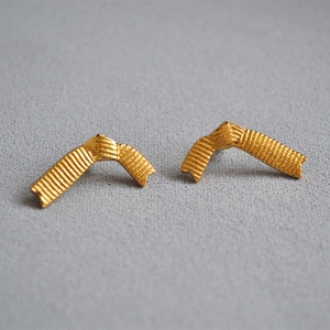 Detailed macro view of 18K gold plated ribbon stud earrings with vertical striped texture