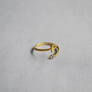 Detail of adjustable gold ring featuring a letter P and a round sparkling zircon stone