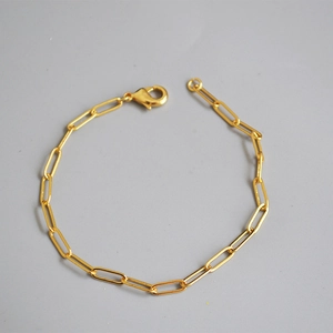 Detailed close-up of a minimalist gold paperclip link bracelet with a lobster clasp