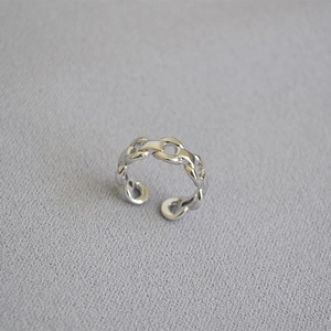 Vue détaillée de dessus d'une bague chaîne en argent poli sur un tissu gris