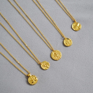 Detailed view of five vintage gold coin necklaces with embossed swan and bee motifs