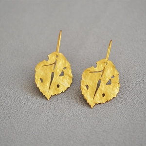 Detailed view of hammered gold leaf earrings with a textured matte finish and creative cut-outs