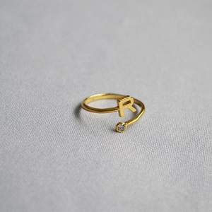 Close-up of golden initial R open ring with micro-set round zircon stone detail