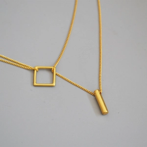 Golden double-layer necklace with geometric square and cylindrical pendant design