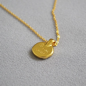 Macro shot of gold coin pendant engraved with Love Forever and floral pattern