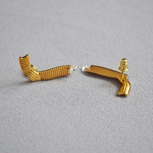 Detail of 18K gold-plated ribbon earrings with fine horizontal texture and bullet backings