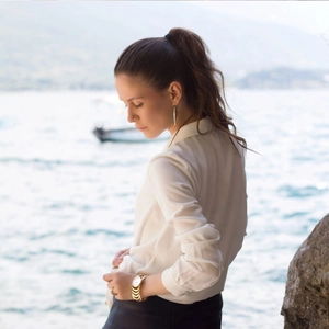 Elegant gold link watch and long drop earrings set on model against a sunny lake view
