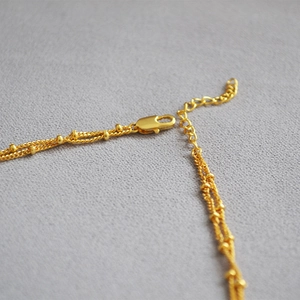 Macro detail of 18K gold plated brass double layer necklace with beads and lobster clasp