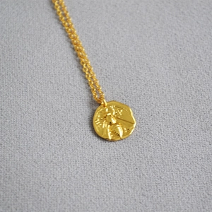 Golden necklace featuring a round gold coin pendant with an embossed honeybee relief