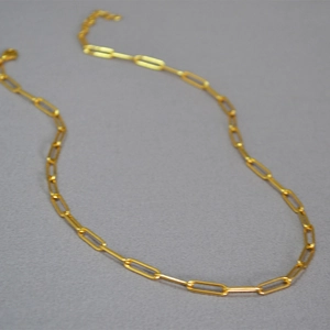 Detailed close-up of a gold paperclip link choker necklace with adjustable chain tail