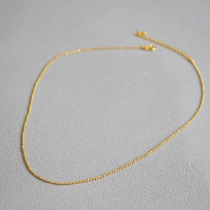 Minimalist golden beaded choker necklace with faceted metal balls and lobster clasp