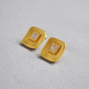 Elegant 18K gold plated square zircon stud earrings on textured fabric background