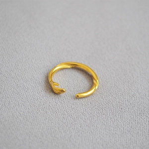 Close-up of a minimalist gold-plated adjustable ring featuring a unique hugging hand design