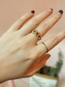 Close-up of vintage gold rings with green emerald gemstones and delicate white pearls