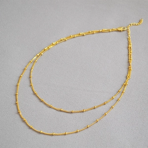 Detail of 18K gold plated brass double layer necklace with polished small beads and lobster clasp