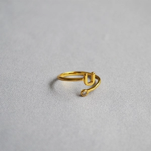Detailed shot of golden adjustable ring featuring a letter U design and a small zircon stone