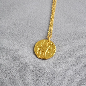 Golden coin necklace with embossed deer and star pendant on a delicate cable chain