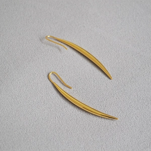 Detailed view of long polished gold-plated brass drop earrings with sleek curved design