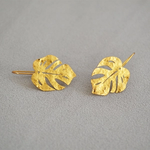 Detailed macro view of matte brushed gold monstera leaf earrings with textured finish