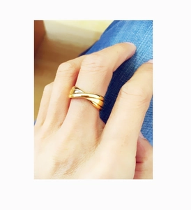 Detail of gold-plated triple crossover ring featuring a sleek mirror-polished finish