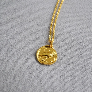 Close-up of gold vintage coin pendant featuring owl and crescent moon relief