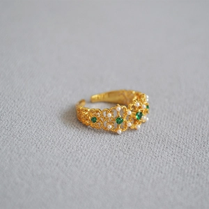 Vintage royal style gold lace ring featuring emerald stones and white pearls in macro view