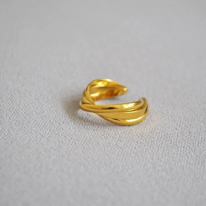 Detailed macro view of triple-layered twisted gold-plated brass ring on textured fabric