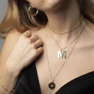 Minimalist gold chain necklace with large M letter and star disc pendants in layered style