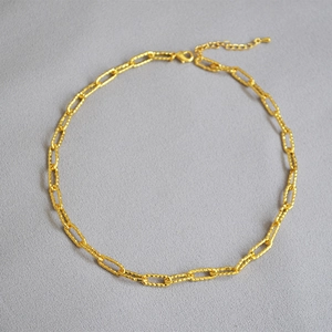 Détail du collier chaîne dorée avec maillons torsadés et fermoir mousqueton ajustable
