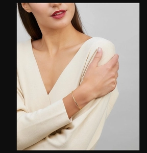 Detail of elegant gold plated bamboo style thin bangle worn on a female wrist