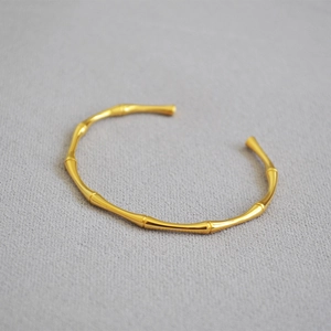 Detail of minimalist gold-plated bamboo joint bangle showing elegant textured knots