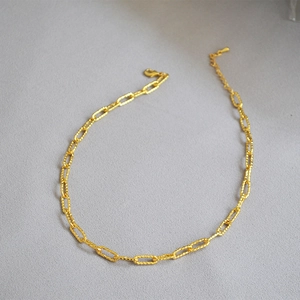 Détail du collier à maillons dorés avec texture torsadée et fermoir mousqueton
