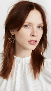 Detailed view of large gold cutout star earrings with small solid star studs on model