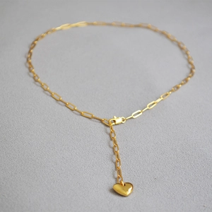 Macro view of gold paperclip chain necklace with 3D heart pendant and lobster clasp
