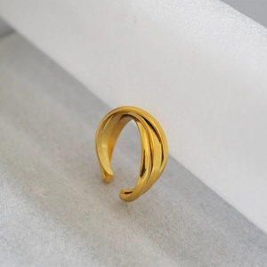 Macro shot of gold-plated triple cross-winding ring on textured base with polished finish