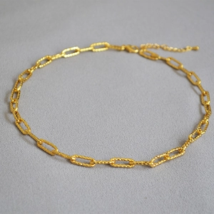 Détail du collier à maillons trombone dorés avec texture martelée et fermoir mousqueton