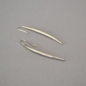 Close-up of long polished silver teardrop earrings with a sleek minimalist hook design