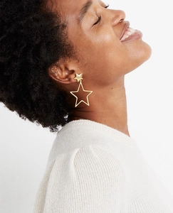 Detailed close-up of a model wearing gold hollow star dangle earrings in a retro style