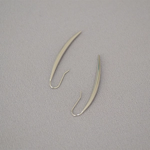 Macro detail of curved crescent hoop earrings in polished brass with gold plating