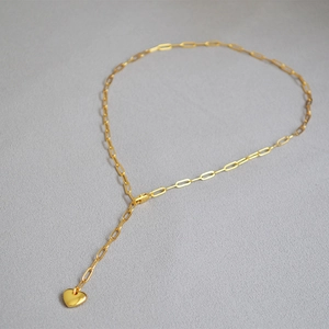 Close-up of golden paperclip chain with 3D heart pendant in a Y-shaped necklace design