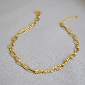Détail macro d'un collier chaîne trombone plaqué or avec maillons rectangulaires
