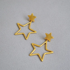 Detail of gold hollow star drop earrings featuring a polished finish and minimalist design