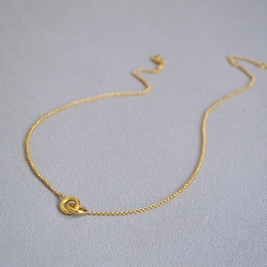Close-up of gold minimalist double interlocking rings pendant on fine cross chain