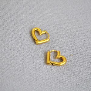 Vue détaillée de boucles d'oreilles cœur dorées avec un design poli et ajouré