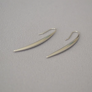 Macro shot of minimalist polished silver tapered teardrop earrings on grey fabric
