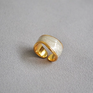 Minimalist wide open ring featuring golden metal luster and marble white enamel finish